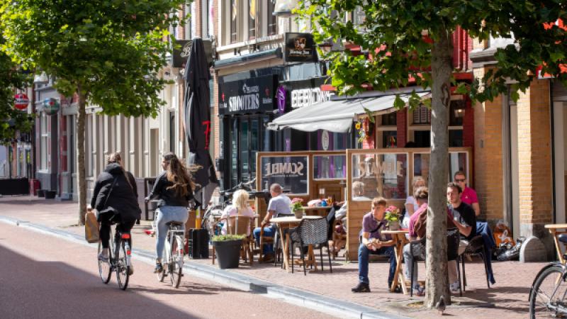 Twee mensen fietsen langs een zonnig terras