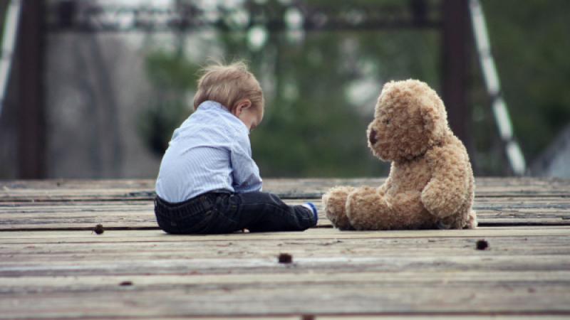 Jongetje zit buiten met knuffelbeer
