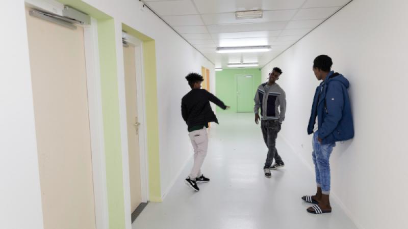 Drie jonge asielzoekers met elkaar in gesprek op de gang van de woonvoorziening