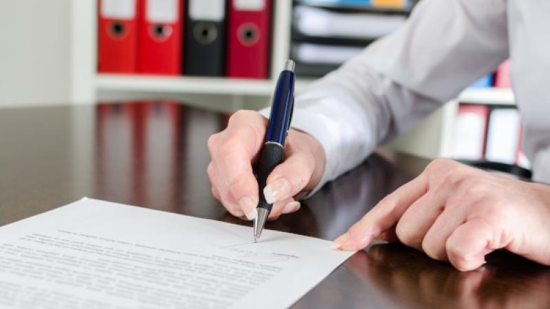 Close-up van hand die document ondertekent