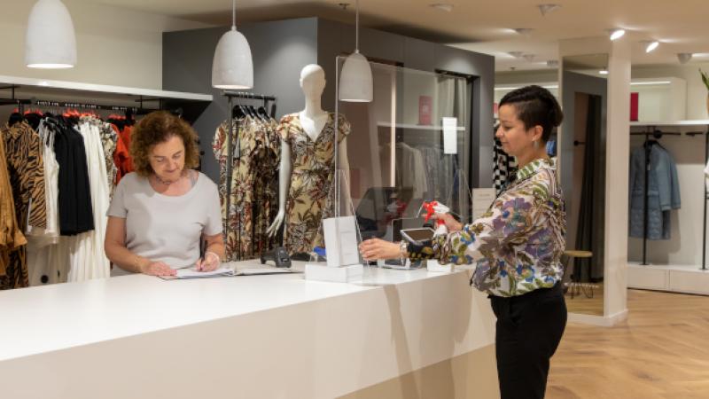 ondernemer en medewerker bij de toonbank in een kledingzaak