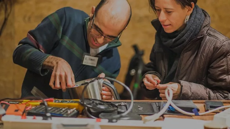 Een man en een vrouw repareren een elektrisch apparaat