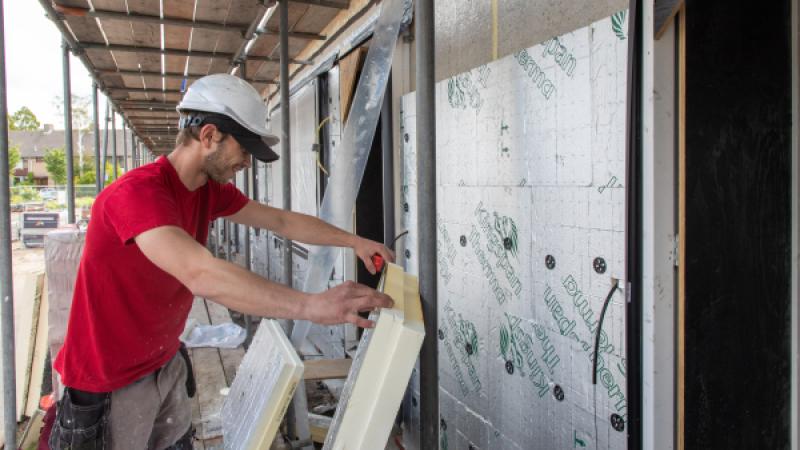 Man met helm werkt aan de bouw van een huis