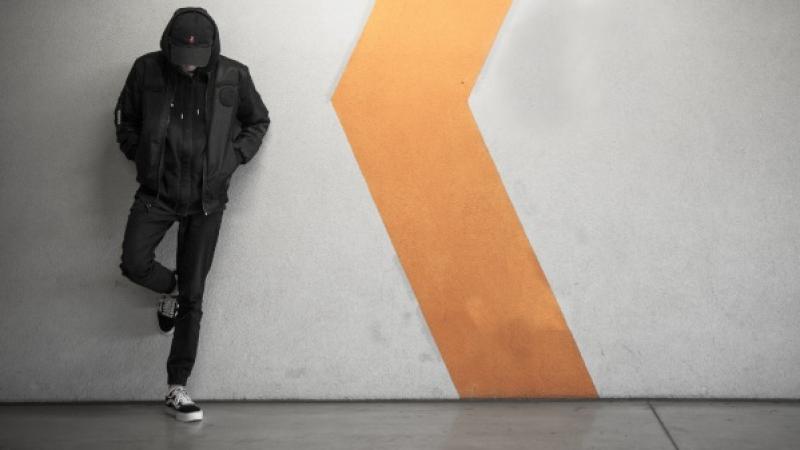man staat met geboden hoofd geleund tegen een muur
