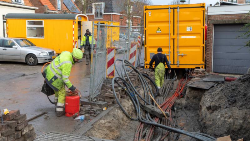 In een opengebroken straat worden elektriciteitskabels gelegd