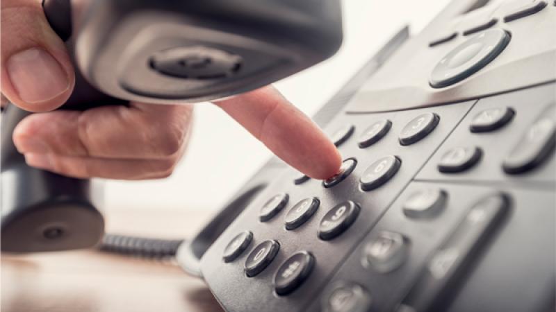 Iemand tikt een telefoonnummer in op een vast telefoontoestel