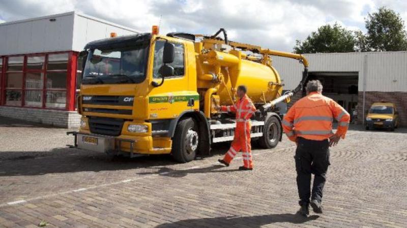 twee ambtenaren van de buitendienst bij kolkenzuiger