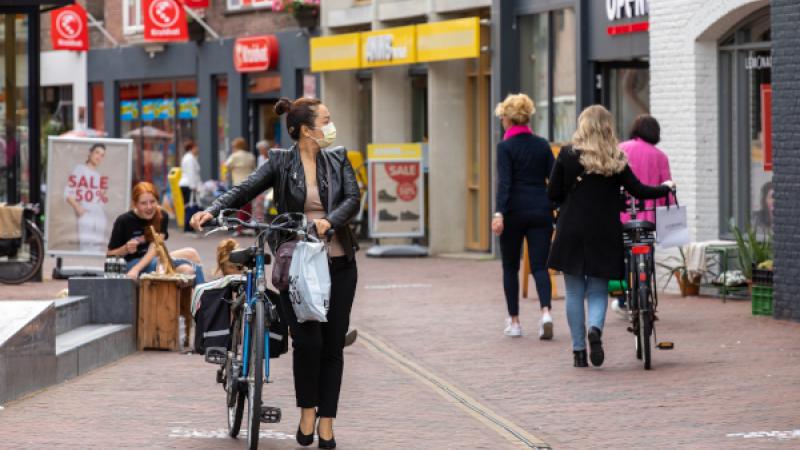 vrouw in winkelstraat met mondkapje