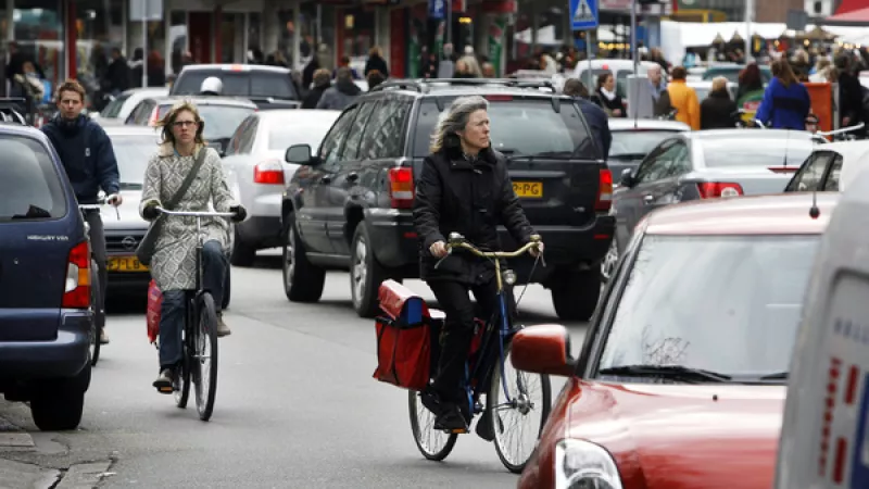 fietser en auto's op drukke weg in een stad