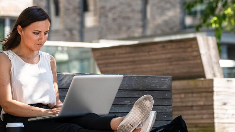 vrouw zit op bank en kijkt naar laptop
