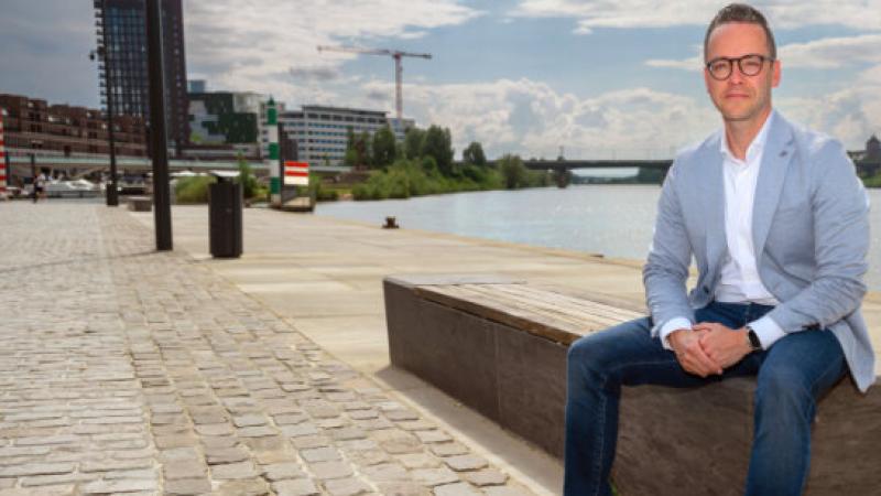 wethouder Erwin Boom zit op een bankje aan de kade van een rivier