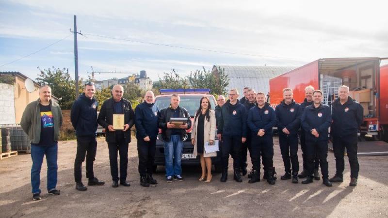 Mensen poseren voor een brandweerauto en een vrachtwagen