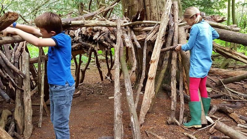 Jongetje en meisje maken een hutconstructie van takken in het bos