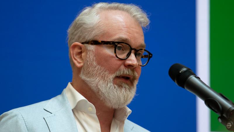 Close up-foto (gezicht + microfoon) van Joh Bijl tijdens zijn lezing
