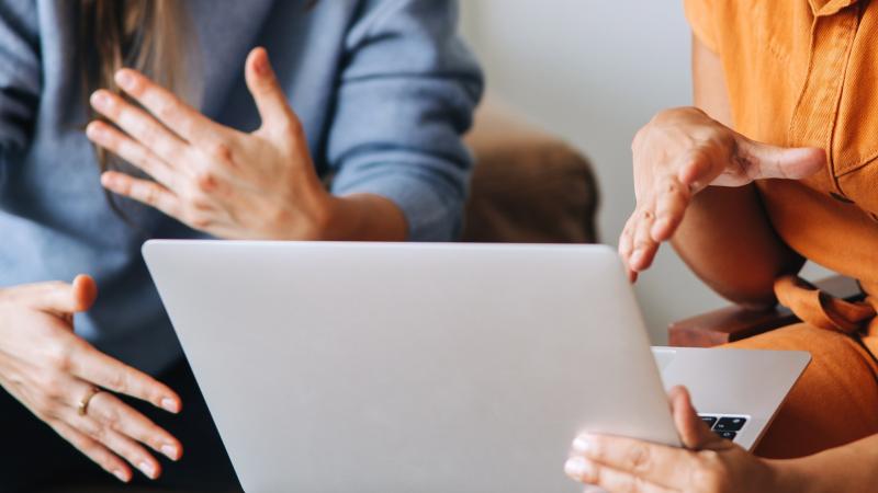 2 mensen zijn in gesprek met elkaar voor een laptop