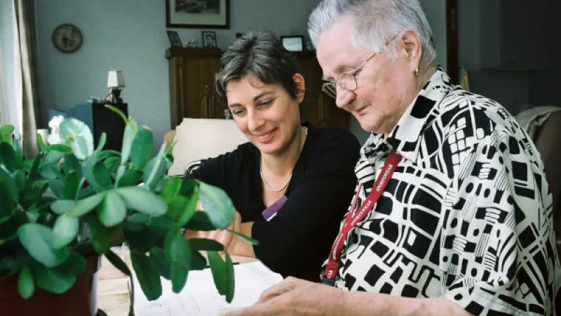 jonge en oudere vrouw met elkaar in gesprek aan huiskamertafel