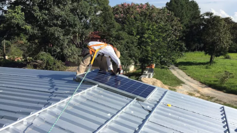 Man installeert zonnepaneel op een dak