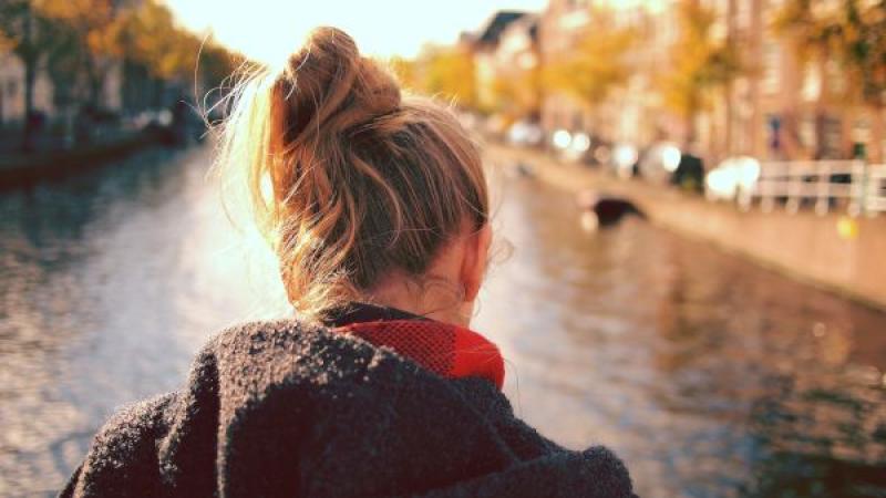 Meisje kijkt uit over gracht (op de rug gezien, gebogen hoofd)
