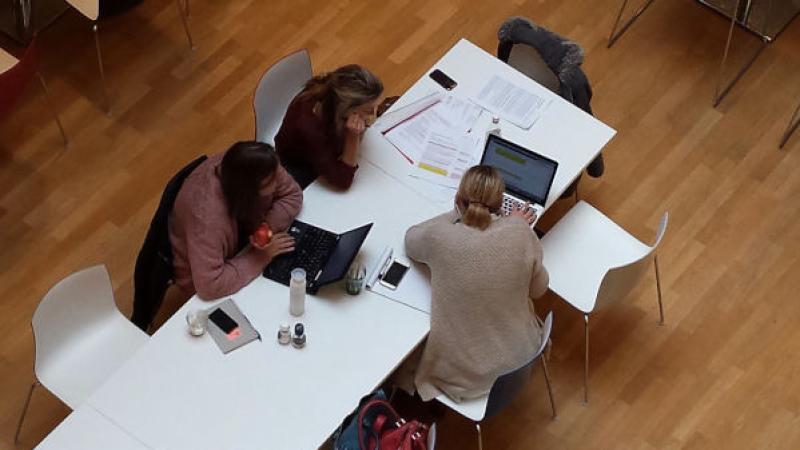bovenaanzicht van twee vrouwen en een man in overleg met laptops bij de hand