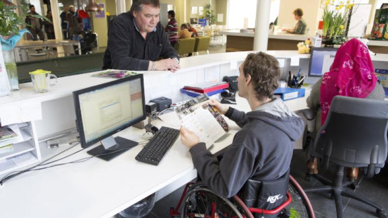 jongen in rolstoel bij aangepaste werkplek gemeente