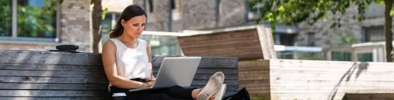 vrouw zit op bank en kijkt naar laptop