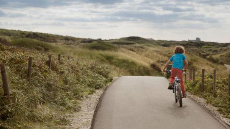 Kind op fiets door duinen