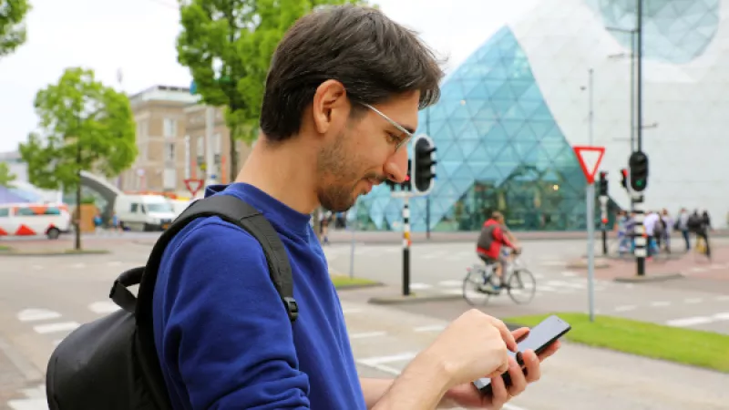 Man checkt zijn smart phone op straat