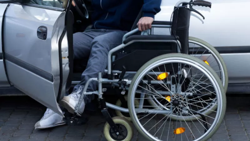 Man stapt uit auto in rolstoel