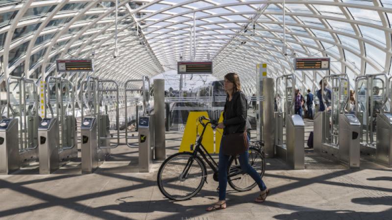 Fietser loopt langs poortjes van metrostation