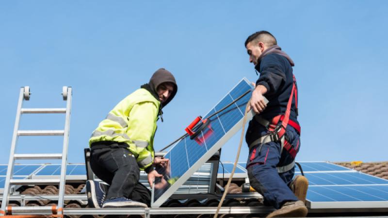 Twee mannen installeren zonnepanelen op een dak