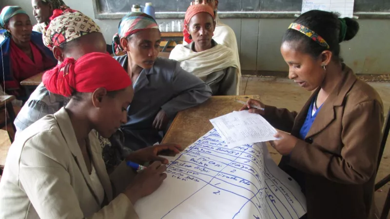 Ethiopische vrouwen maken schema op een flipovervel