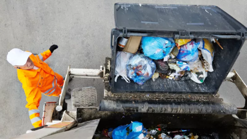 Bovenaanzicht op een vuilniscontainer die in een vuilniswagen wordt geleegd