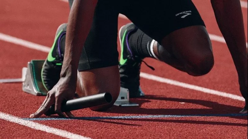 atleet met estafettestokje in de startblokken