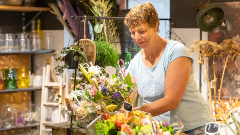 Vrouw zet boeket klaar in bloemenwinkel