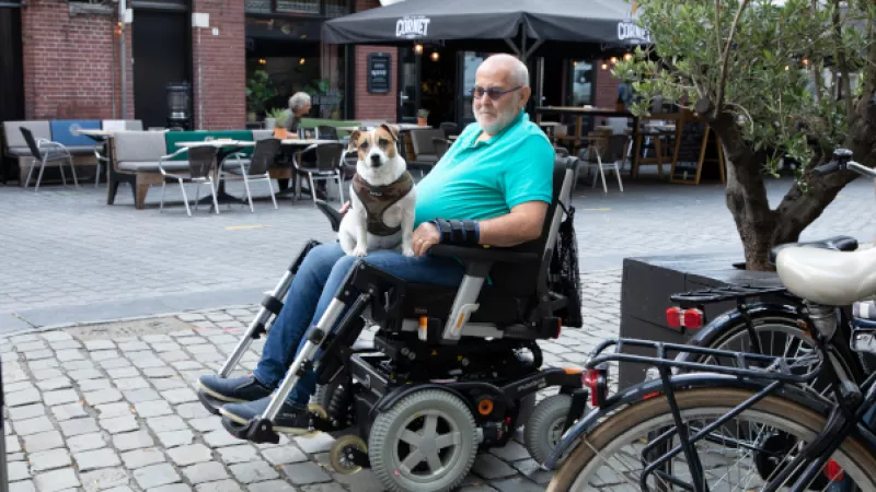 Man in elektrische rolstoel met hond op schoot