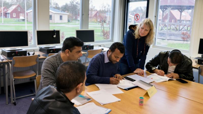 4 statushouders met documenten voor zich op tafel
