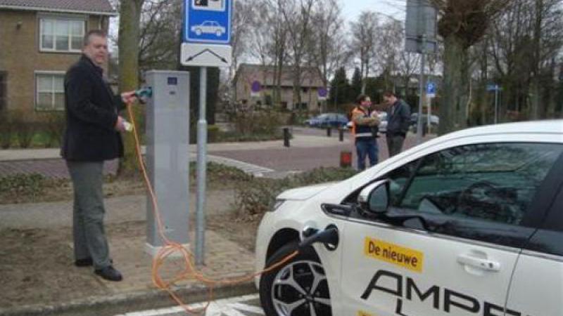 Man plugt stekker van elektrische auto in laadpaal