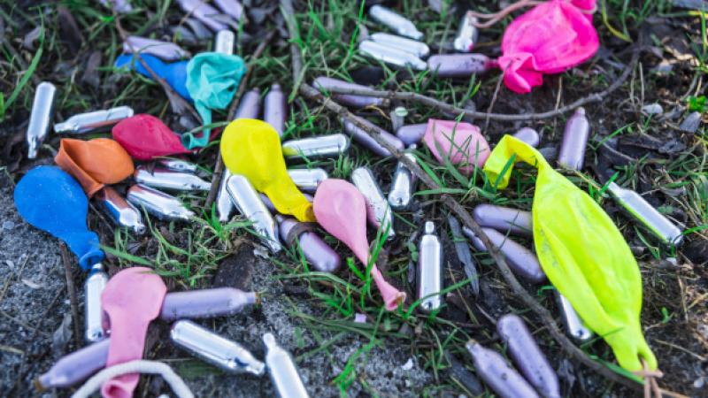 gebruikte lachgasampullen en ballonnen in het gras