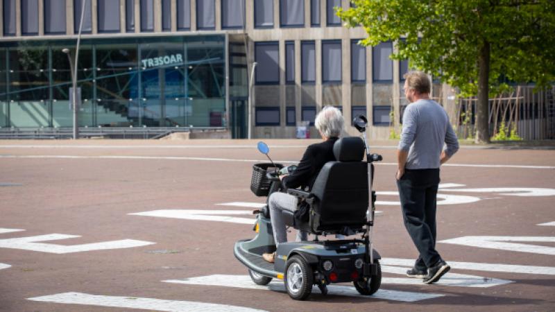 vrouw op scootmobiel en wandelende man