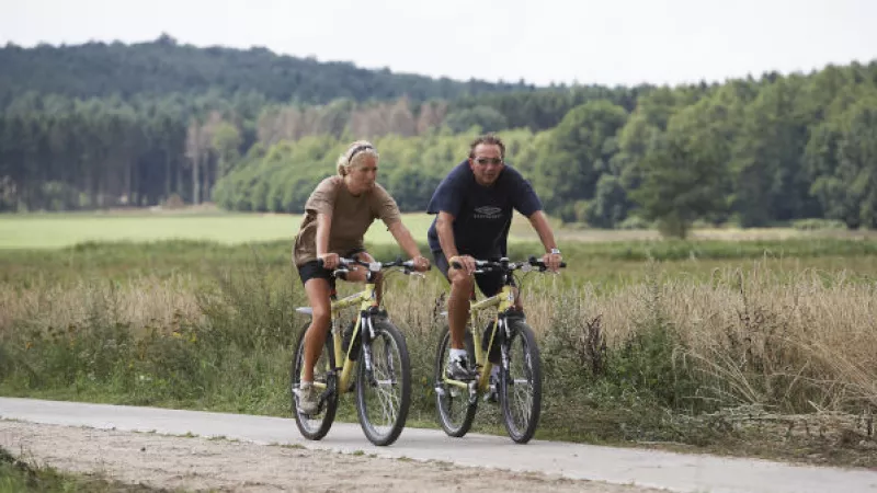 Een vrouw en een man fietsen door een natuurgebied