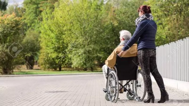 oudere vrouw in rolstoel voortgeduwd door jongere vrouw