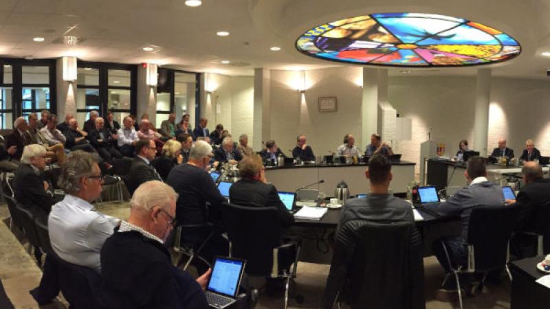 Foto van een gemeenteraad in vergadering bijeen met publiek erbij