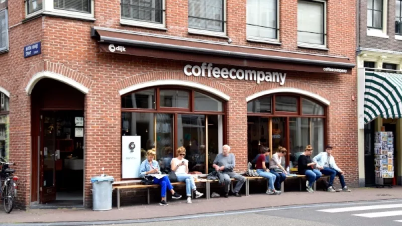 Mensen zitten op een bank voor een café