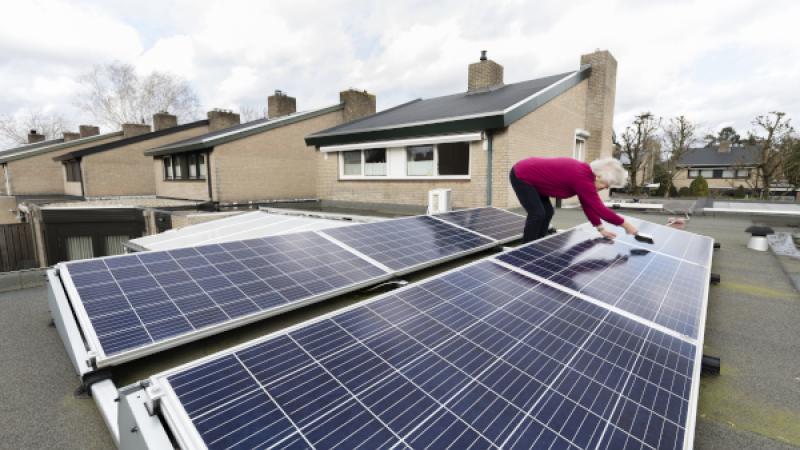 Vrouw maakt de zonnepanelen op het dak van haar huis schoon