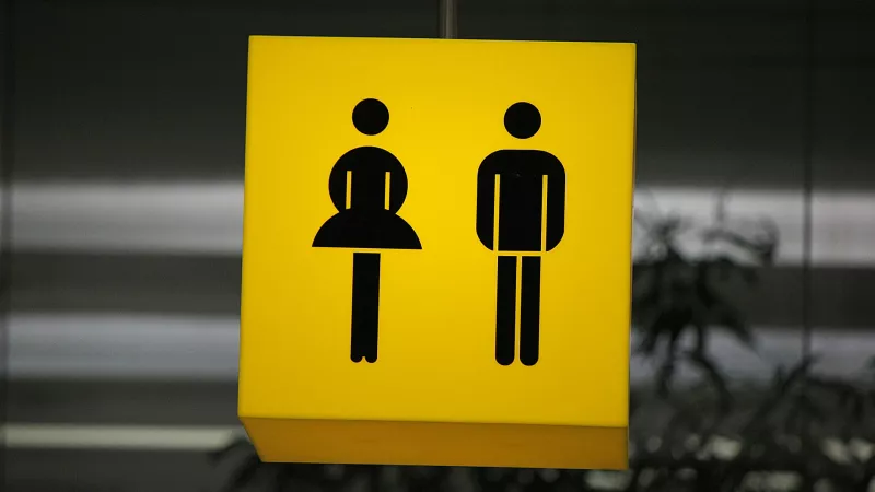 bord voor een openbaar toegankelijk toilet: m/v-symbool tegen gele achtergrond