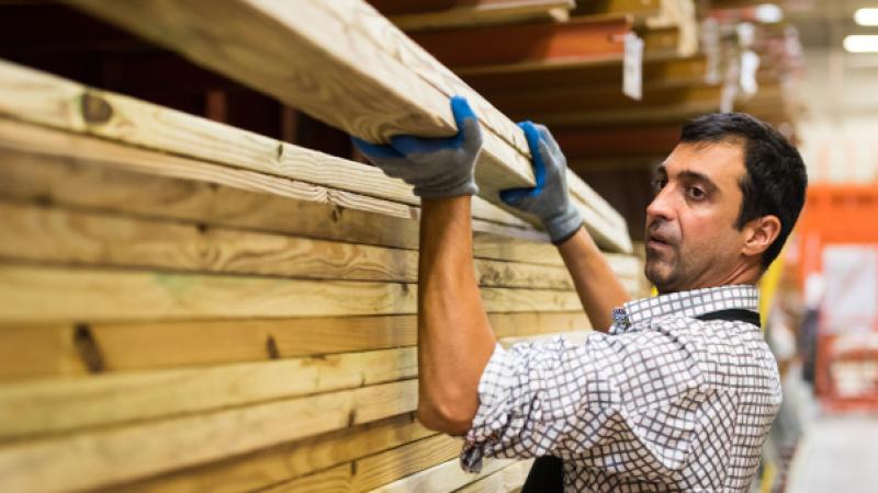 Man haalt houten balken uit een magazijn