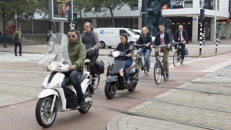 Fietsers en scooters steken een trambaan over