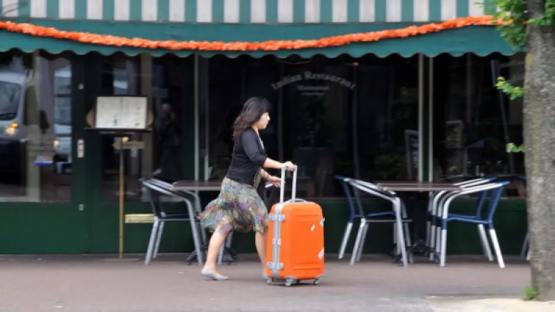 Vrouw loopt met rolkoffer op straat