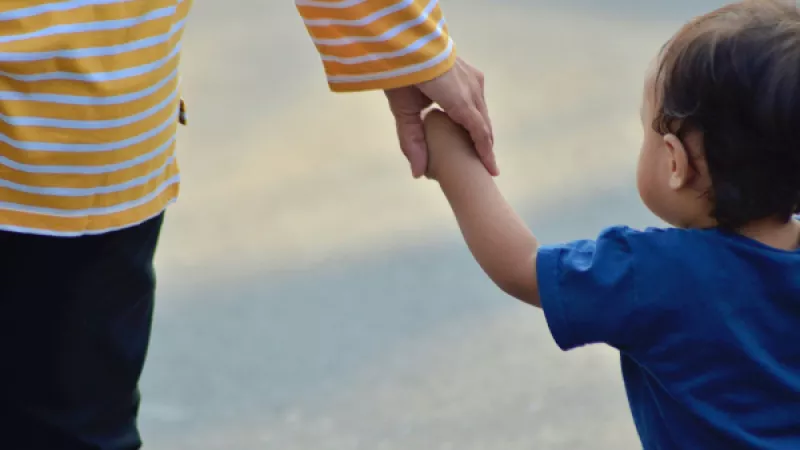 Klein kindje houdt op straat de hand vast van ouder