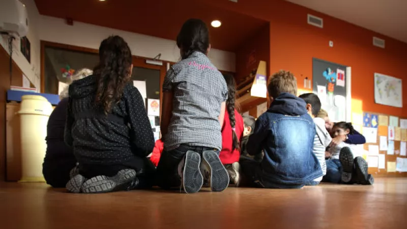 Groepje kinderen zitten op de grond in een klaslokaal